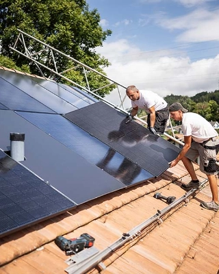 Arbeiter installieren eine Solaranlage auf einem Eigenheim. 